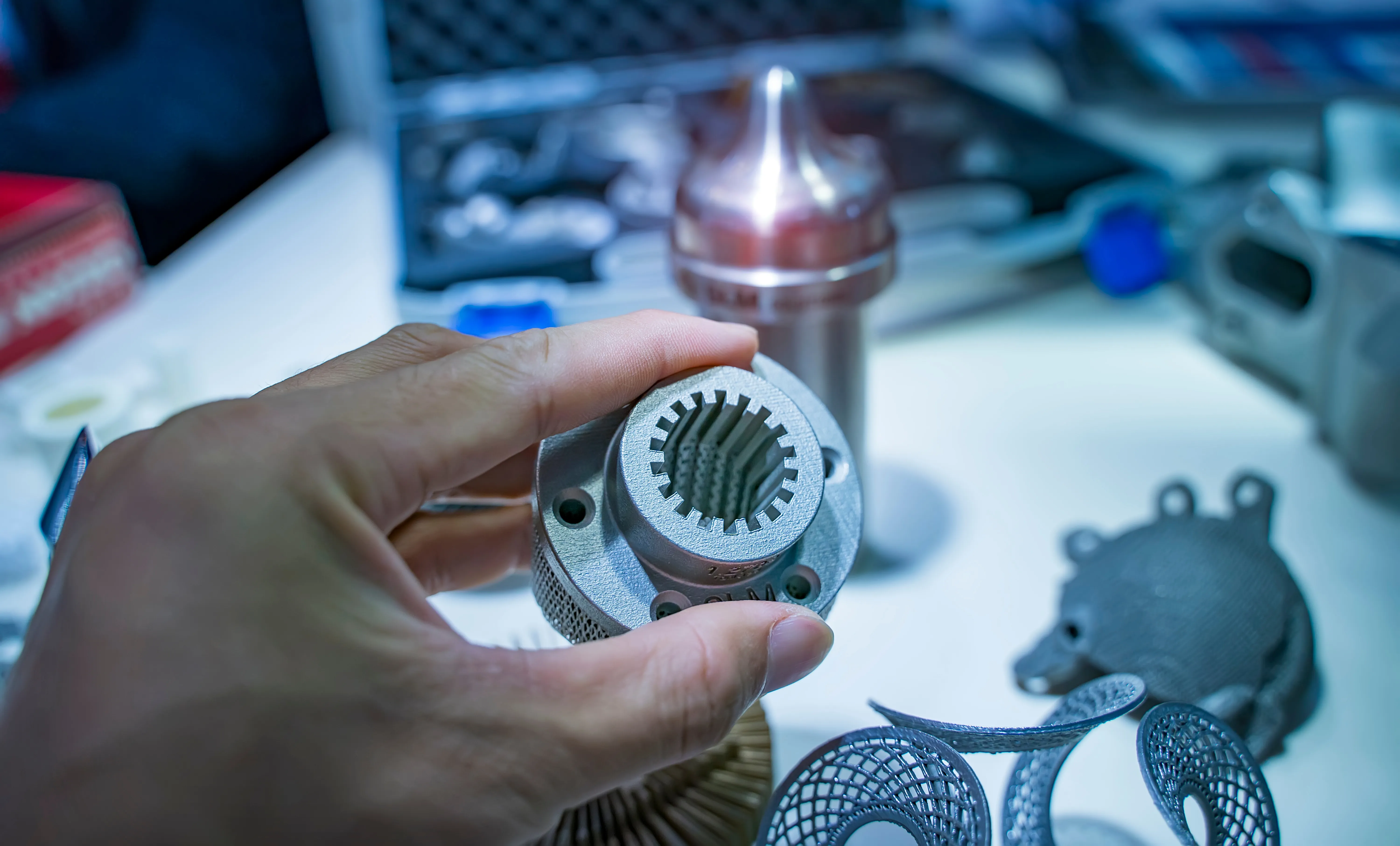 Hand holding a 3D-printed metal part with intricate detail